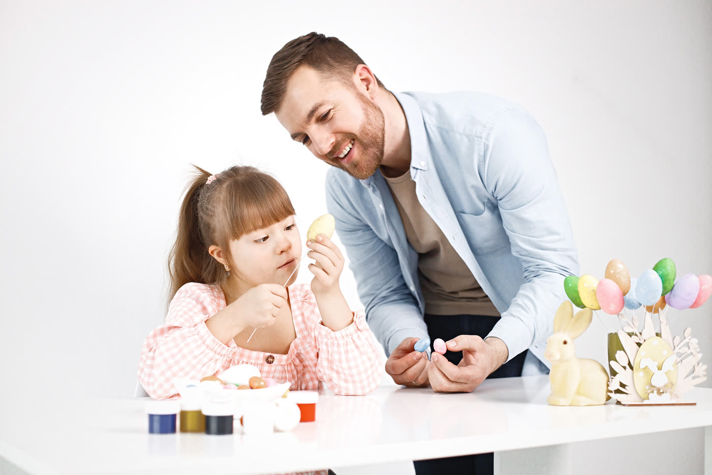 A father and his daughter, who has Down syndrome, smiling together in their kitchen