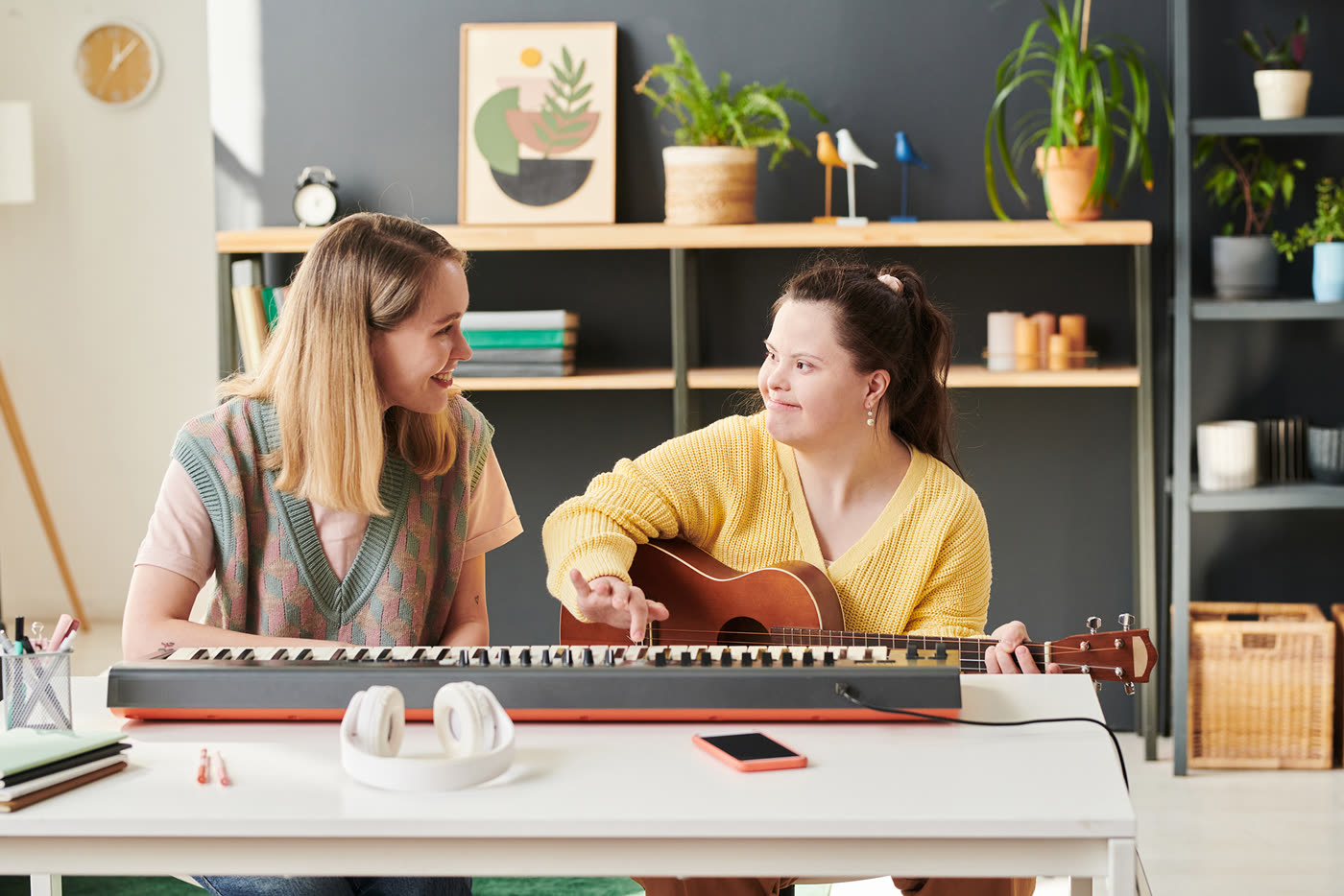 A support worker teaching a young woman to play guitar